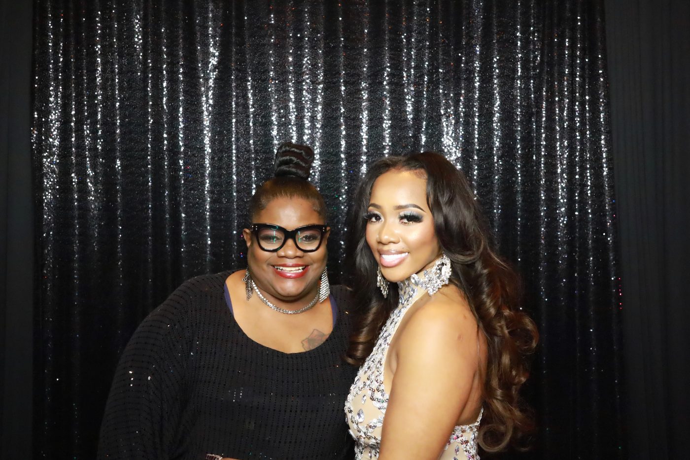Two guests at a formal gala photo booth with silver sequin backdrop