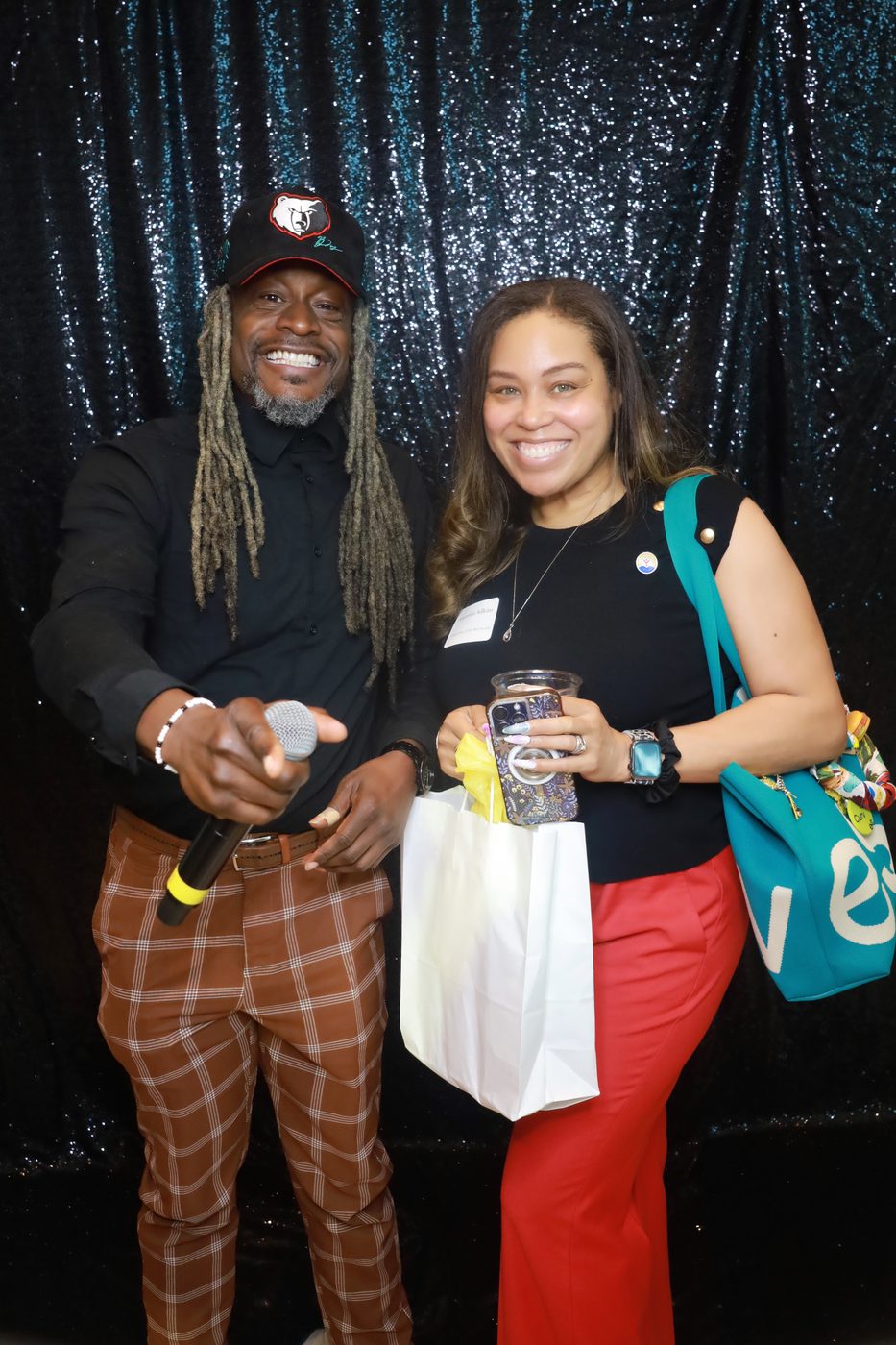 Event host and guest at a teal sequin photo booth backdrop